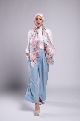 Hijabi Model walking in EMMA scarf Honey Blooms satin, a print of bees and delicate pink flowers with a pink border.