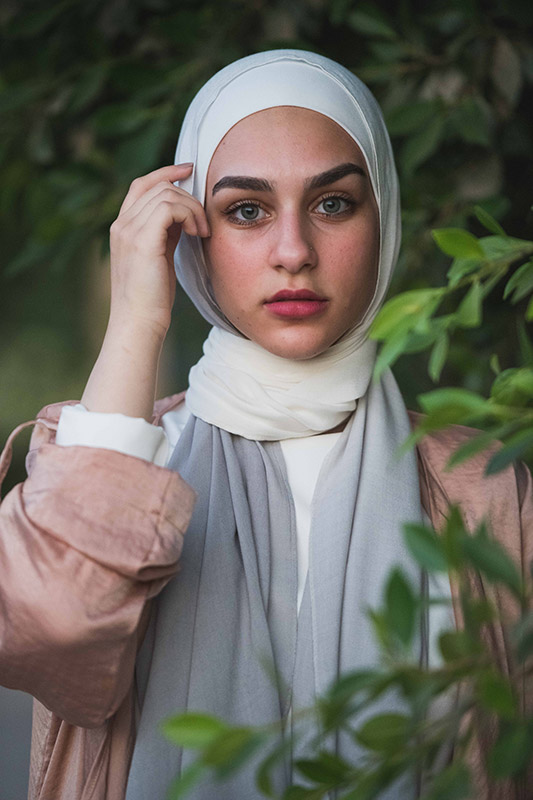 A close up of a hijabi girl in EMMA scarf Powdered Slate with her pointer finger on her temple